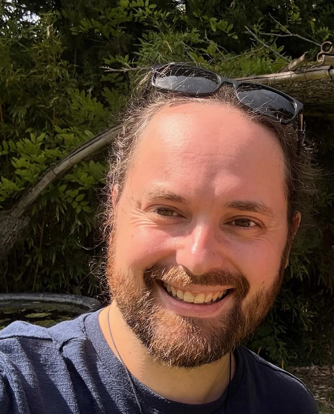 Kevin Legros, souriant, en plein air devant un feuillage.